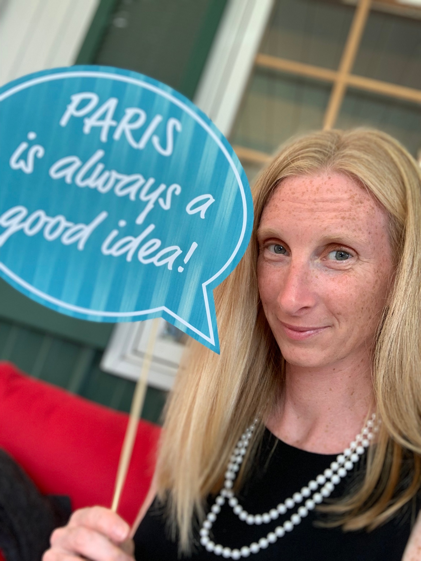 Elizabeth holding a sign that reads Paris is always a good idea